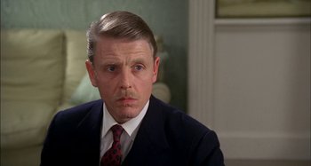 Movie still from “The Mirror Crack'd” (1980), directed by Guy Hamilton – A person wearing a suit and tie; Close Up shot, Over the shoulder angle