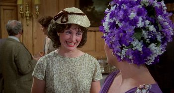 Movie still from “The Mirror Crack'd” (1980), directed by Guy Hamilton – A woman wearing a straw hat talking to another woman wearing a purple hat; Close Up shot, Over the shoulder angle