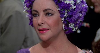 Movie still from “The Mirror Crack'd” (1980), directed by Guy Hamilton – A person wearing a flower crown; Close Up shot, Over the shoulder angle