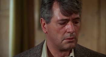 Movie still from “The Mirror Crack'd” (1980), directed by Guy Hamilton – A person wearing a suit and tie; Close Up shot, Over the shoulder angle