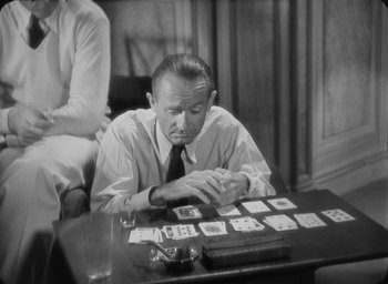Movie still from “The Most Dangerous Game” (1932), directed by Irving Pichel – A black and white photo of a man sitting at a table with playing cards; Medium shot, High angle