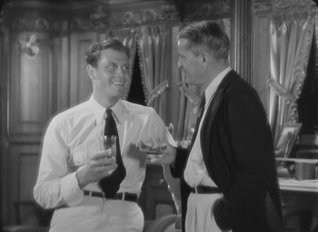 Movie still from “The Most Dangerous Game” (1932), directed by Irving Pichel – Two men are having a conversation while holding wine glasses; Medium shot, Over the shoulder angle