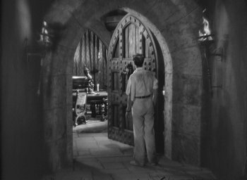 Movie still from “The Most Dangerous Game” (1932), directed by Irving Pichel – A man standing in front of an arched doorway; Wide shot, High angle
