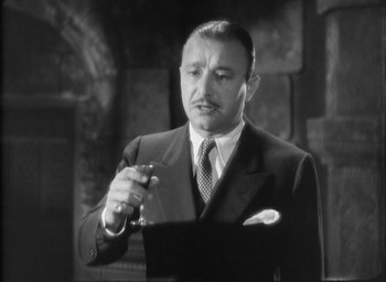 Movie still from “The Most Dangerous Game” (1932), directed by Irving Pichel – A man in a suit and tie holding a glass; Close Up shot, Low angle