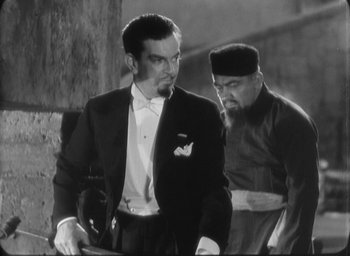 Movie still from “The Most Dangerous Game” (1932), directed by Irving Pichel – A man in a suit and a man in a hat; Medium shot, Over the shoulder angle