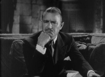 Movie still from “The Most Dangerous Game” (1932), directed by Irving Pichel – An older man sitting on a couch with his hand on his chin; Close Up shot, High angle