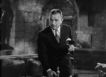 Movie still from “The Most Dangerous Game” (1932), directed by Irving Pichel – A man in a suit and tie smoking a cigarette; Medium shot, High angle