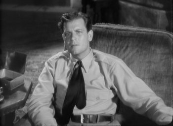 Movie still from “The Most Dangerous Game” (1932), directed by Irving Pichel – A black and white photo of a man sitting in a chair wearing a tie; Medium shot, Low angle