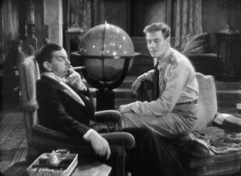 Movie still from “The Most Dangerous Game” (1932), directed by Irving Pichel – Two men sitting on a chair in front of a globe; Medium shot, High angle