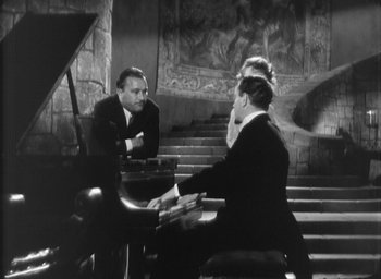 Movie still from “The Most Dangerous Game” (1932), directed by Irving Pichel – A man and a woman sitting in front of a grand piano; Wide shot, High angle