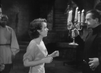 Movie still from “The Most Dangerous Game” (1932), directed by Irving Pichel – A woman standing next to a man in front of a candelabrum; Medium shot, Low angle
