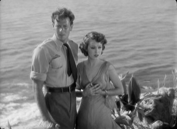 Movie still from “The Most Dangerous Game” (1932), directed by Irving Pichel – A man and a woman standing next to a body of water; Medium shot, High angle