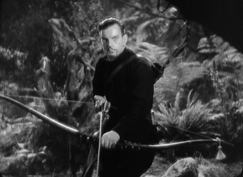 Movie still from “The Most Dangerous Game” (1932), directed by Irving Pichel – A black and white photo of a man holding a bow and arrow; Medium shot, Low angle