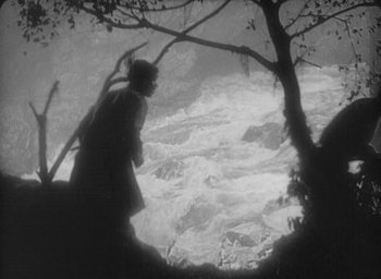 Movie still from “The Most Dangerous Game” (1932), directed by Irving Pichel – A man standing on top of a tree next to a river; Extreme Wide shot, High angle