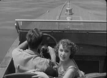 Movie still from “The Most Dangerous Game” (1932), directed by Irving Pichel – A man and a woman driving a boat on the water; Medium shot, High angle