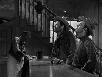 Movie still from “The Ox-Bow Incident” (1942), directed by William A. Wellman – Three men in cowboy hats are standing at a counter; Medium shot, Low angle
