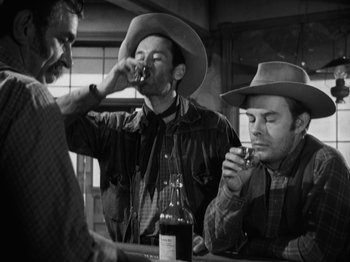 Movie still from “The Ox-Bow Incident” (1942), directed by William A. Wellman – A group of men in cowboy hats drinking wine; Medium shot, Over the shoulder angle