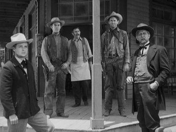 Movie still from “The Ox-Bow Incident” (1942), directed by William A. Wellman – A black and white photo of a group of men standing on a porch; Wide shot, Low angle