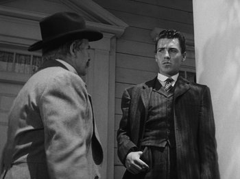 Movie still from “The Ox-Bow Incident” (1942), directed by William A. Wellman – A man in a suit and a man in a hat talking to each other; Medium shot, Low angle