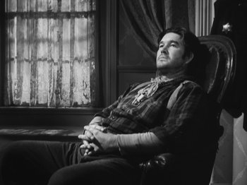 Movie still from “The Ox-Bow Incident” (1942), directed by William A. Wellman – A black and white photo of a man sitting in a chair; Medium shot, Low angle