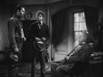 Movie still from “The Ox-Bow Incident” (1942), directed by William A. Wellman – A group of men standing next to each other in front of a window; Medium shot, Over the shoulder angle