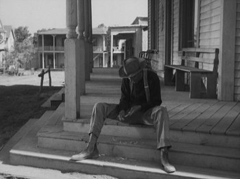 Movie still from “The Ox-Bow Incident” (1942), directed by William A. Wellman – A man sitting on the steps of an old house; Wide shot, Low angle