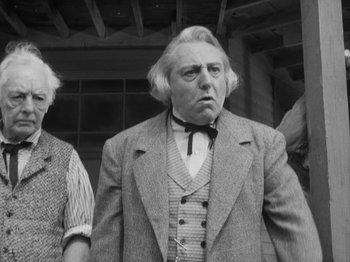 Movie still from “The Ox-Bow Incident” (1942), directed by William A. Wellman – An older man in a suit and tie standing in front of a building; Medium shot, Low angle