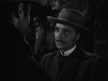 Movie still from “The Ox-Bow Incident” (1942), directed by William A. Wellman – A man with a mustache wearing a suit and a hat; Close Up shot, Over the shoulder angle