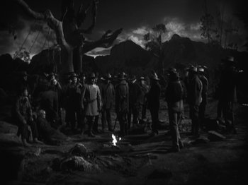 Movie still from “The Ox-Bow Incident” (1942), directed by William A. Wellman – A group of people standing around a fire; Wide shot, High angle