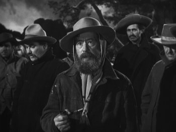 Movie still from “The Ox-Bow Incident” (1942), directed by William A. Wellman – A group of men standing next to each other wearing hats; Medium shot, Low angle