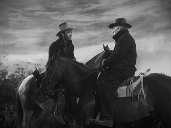 Movie still from “The Ox-Bow Incident” (1942), directed by William A. Wellman – Two men sitting on top of horses in a black and white photo; Medium shot, Over the shoulder angle