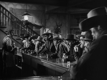 Movie still from “The Ox-Bow Incident” (1942), directed by William A. Wellman – A black and white photo of a group of men sitting at a bar; Wide shot, Low angle