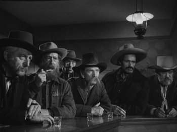 Movie still from “The Ox-Bow Incident” (1942), directed by William A. Wellman – A black and white photo of a group of men sitting at a bar; Medium shot, Low angle