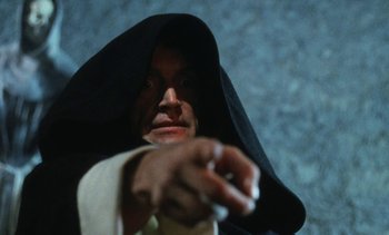 Movie still from “The Pit and the Pendulum” (1991), directed by Stuart Gordon – A man wearing a black robe and a black hood; Close Up shot, Low angle