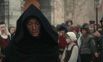 Movie still from “The Pit and the Pendulum” (1991), directed by Stuart Gordon – A crowd of people standing around a building; Medium shot, High angle