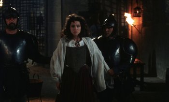 Movie still from “The Pit and the Pendulum” (1991), directed by Stuart Gordon – A woman standing next to a man wearing a suit of armor; Medium shot, Over the shoulder angle