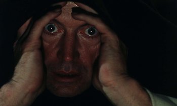 Movie still from “The Pit and the Pendulum” (1991), directed by Stuart Gordon – A man with his hands on top of his head; Extreme Close Up shot, Overhead angle