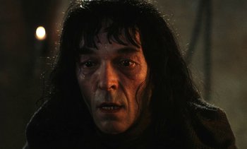Movie still from “The Pit and the Pendulum” (1991), directed by Stuart Gordon – A person with long black hair; Close Up shot, Low angle