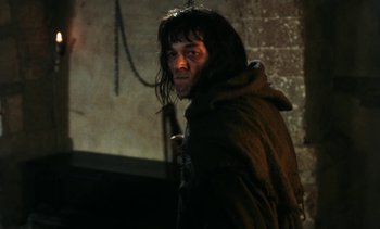 Movie still from “The Pit and the Pendulum” (1991), directed by Stuart Gordon – A man with long black hair wearing a hooded jacket; Medium shot, Low angle
