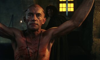 Movie still from “The Pit and the Pendulum” (1991), directed by Stuart Gordon – A bald man with blood all over his body; Medium shot, Low angle
