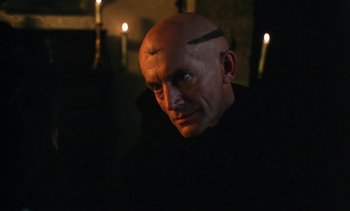 Movie still from “The Pit and the Pendulum” (1991), directed by Stuart Gordon – A man with a shaved head is looking at the camera; Close Up shot, Low angle