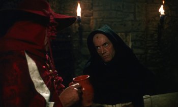 Movie still from “The Pit and the Pendulum” (1991), directed by Stuart Gordon – A man in a black robe holding a red mug; Medium shot, Over the shoulder angle