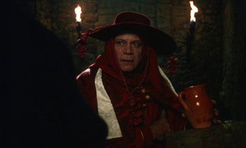 Movie still from “The Pit and the Pendulum” (1991), directed by Stuart Gordon – A man in a red robe and a red hat; Close Up shot, Over the shoulder angle