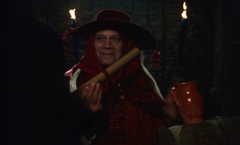 Movie still from “The Pit and the Pendulum” (1991), directed by Stuart Gordon – An old woman holding a wooden stick in her hands; Medium shot, Over the shoulder angle