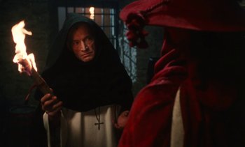 Movie still from “The Pit and the Pendulum” (1991), directed by Stuart Gordon – A man in a hooded cloak and a red robe; Medium shot, Over the shoulder angle
