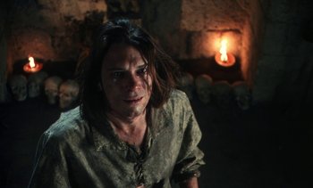 Movie still from “The Pit and the Pendulum” (1991), directed by Stuart Gordon – A man with long brown hair is standing in a room; Close Up shot, High angle