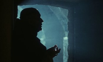 Movie still from “The Pit and the Pendulum” (1991), directed by Stuart Gordon – A man standing in front of a window in the dark; Close Up shot, Low angle
