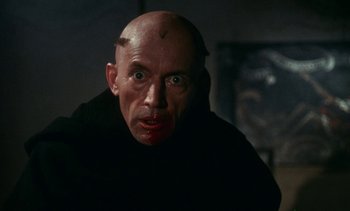Movie still from “The Pit and the Pendulum” (1991), directed by Stuart Gordon – A man with a shaved head and a bald head; Close Up shot, Over the shoulder angle