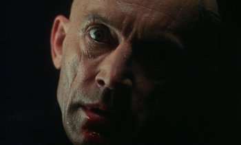 Movie still from “The Pit and the Pendulum” (1991), directed by Stuart Gordon – A man's face with blood on his face; Extreme Close Up shot, Low angle
