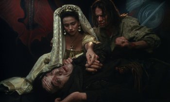 Movie still from “The Pit and the Pendulum” (1991), directed by Stuart Gordon – A man and two women in medieval garb; Medium shot, High angle